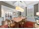 Elegant dining room with a rustic wood table, coffered ceilings, modern lighting, and large windows with shutters at 6506 Jepson Ct # 349, Charlotte, NC 28214