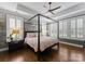 Serene main bedroom with a tray ceiling, canopy bed, hardwood floors, and plantation shutters at 6506 Jepson Ct # 349, Charlotte, NC 28214