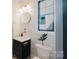 Chic half bathroom featuring a sleek black vanity, gold fixtures, and a decorative mirror, enhancing guest appeal at 705 Mcalway Rd, Charlotte, NC 28211