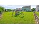 Large backyard with lush green grass and a vibrant playset under a clear blue sky at 8312 Compton Acres Ln, Waxhaw, NC 28173