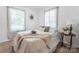 Bright bedroom featuring a comfortable bed, light hardwood floors, and natural light from the two well-lit windows at 909 Gibbons St, Gastonia, NC 28052