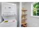 Bright laundry room features modern washer and dryer, and natural wood shelves for storage at 909 Gibbons St, Gastonia, NC 28052