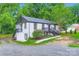 View of a two-story white brick home with black trim, showcasing well-maintained landscaping at 1224 E Woodlawn Rd, Charlotte, NC 28209
