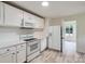 Bright kitchen featuring white cabinets, appliances, and light-colored countertops with hardwood floors at 1224 E Woodlawn Rd, Charlotte, NC 28209