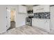 Efficient kitchenette featuring white cabinets, stainless steel appliances, and a stylish backsplash at 1224 E Woodlawn Rd, Charlotte, NC 28209