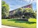 Serene view of the brick condo building surrounded by mature trees and a lush lawn, offering peaceful living at 1300 Queens Rd # 409, Charlotte, NC 28207