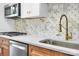 Close up of modern kitchen featuring stainless steel appliances, custom backsplash, and quartz countertops at 1300 Queens Rd # 409, Charlotte, NC 28207