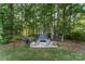 Backyard fire pit with bench seating and a grill area, surrounded by tall trees at 1622 Brookstone Dr, Hickory, NC 28602
