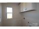 Functional laundry room featuring overhead cabinets, a window, and crisp white walls at 1821 Augustine St, Monroe, NC 28112