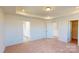 Bright main bedroom with tray ceiling, plush carpet, and an ensuite bathroom at 1821 Augustine St, Monroe, NC 28112