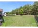 View of a well-maintained backyard featuring a black metal fence, green grass, and mature trees at 2052 Masons Bend Dr, Fort Mill, SC 29708