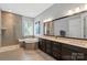Bright bathroom featuring a soaking tub, walk-in shower, and double vanity with dark cabinets and a large mirror at 2052 Masons Bend Dr, Fort Mill, SC 29708