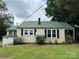 Back exterior view of home with metal roof and green grass at 30497 Orchard Ln, Albemarle, NC 28001
