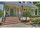 Inviting front porch with brick steps, wrought iron railings, and classic columns, leading to a stylish front door with glass panels at 3165 Pendleton Ave, Charlotte, NC 28210