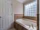 Soaking tub with tile surround, mosaic tile accents, and glass block window for natural light at 3511 Dominion Green Dr, Charlotte, NC 28269