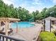 Enjoy the community pool with a slide, seating and lounging areas, surrounded by lush trees on a sunny day at 3511 Dominion Green Dr, Charlotte, NC 28269