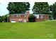 View of a large backyard with a brick house, basketball court, and room to roam at 405 Wesley Heights Dr, Albemarle, NC 28001