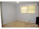 Simple bedroom features light gray walls and carpet, window with blinds, and a floor vent at 405 Wesley Heights Dr, Albemarle, NC 28001