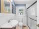 Bathroom featuring white wainscoting, a pedestal sink, and a glass-enclosed shower for a clean aesthetic at 506 Gold St, Shelby, NC 28150