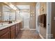 Bathroom featuring double vanity, wooden cabinets, framed mirror, and glass-enclosed shower at 5524 Elk Knob Ct, Denver, NC 28037