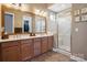 Bathroom featuring double sinks, framed mirror, wooden cabinets, and glass-enclosed shower at 5524 Elk Knob Ct, Denver, NC 28037