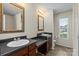 Dual sink bathroom with dark countertops, wooden cabinets, and natural light from a window at 7136 Bullock Dr, Charlotte, NC 28214