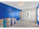 Bright bedroom featuring a large window, neutral carpet, and a striking blue accent wall at 7136 Bullock Dr, Charlotte, NC 28214