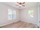 Bright bedroom featuring wood floors, a ceiling fan, and two windows for natural light at 9117 Castle Garden Ln, Charlotte, NC 28215
