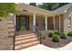 Inviting covered front porch with brick columns, brick steps and mature landscaping at 9117 Castle Garden Ln, Charlotte, NC 28215