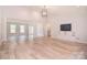 Bright living room boasts light hardwood floors, modern light fixture, and built-in shelving at 9117 Castle Garden Ln, Charlotte, NC 28215