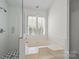 Bright bathroom features a separate shower and soaking tub, complete with window and white tile at 9121 Four Acre Ct, Charlotte, NC 28210