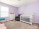 Pastel purple Bedroom featuring a crib, dresser, glider, and natural light at 9123 Magnolia Lily Ave, Charlotte, NC 28227