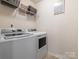 Bright laundry room with washer, dryer, shelving, and decor at 9123 Magnolia Lily Ave, Charlotte, NC 28227