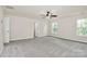 Large carpeted primary bedroom with two windows, ceiling fan and access to primary bathroom at 10304 Ebbets Rd, Charlotte, NC 28273
