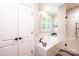 Bright bathroom with a soaking tub, tiled surround, and large window with plantation shutters at 1083 Fox Chase Dr, Newton, NC 28658