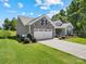 Well-maintained home features lush landscaping, a stone facade, and an attached two-car garage at 117 Autumn Mist Rd, Statesville, NC 28677