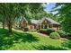 Charming brick home with lush green lawn, manicured landscaping, and mature trees providing shade at 1399 Verdict Ridge Dr, Denver, NC 28037