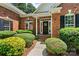 Close-up of a welcoming brick home entrance with black door and manicured shrubs at 1399 Verdict Ridge Dr, Denver, NC 28037