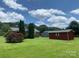 Lush green backyard with a red storage shed and mature trees, offering privacy and space at 1901 Taylor Dr, Gastonia, NC 28052