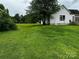 Grassy backyard with mature trees and white house at 211 Oak Dr, Shelby, NC 28150