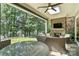 Covered outdoor patio with stone fireplace, ceiling fan, water view, and comfortable wicker furniture at 21319 Baltic Dr, Cornelius, NC 28031
