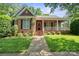 Charming brick home with a well-manicured lawn and inviting front porch, shaded by mature trees on a sunny day at 320 Magnolia St, Davidson, NC 28036