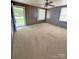 Large bedroom featuring wood paneling, carpet flooring, a ceiling fan, and a door to the exterior at 3412 1St Avenue Nw Cir, Hickory, NC 28601
