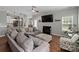 A modern living room with a grey sofa, fireplace, TV, and view of the kitchen at 4408 Overbecks Ln, Waxhaw, NC 28173