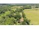Aerial view of the property showcasing a red-roofed house surrounded by green trees and open fields at 495 Brumley Rd, Mooresville, NC 28115