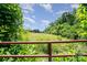 Lush green property featuring open fields and vegetation, framed by a rusty red metal fence at 495 Brumley Rd, Mooresville, NC 28115