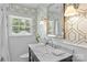 Bright bathroom with geometric wallpaper, white wainscoting, a large window, and a black vanity at 5501 Murrayhill Rd, Charlotte, NC 28210