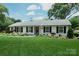 Well-maintained one-story home with fresh green lawn, white painted brick, and beautiful landscaping at 5501 Murrayhill Rd, Charlotte, NC 28210