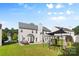 Wide backyard view with home, green grass, patio, playset, seating and manicured landscaping at 5822 Parkstone Dr, Matthews, NC 28104