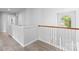 Well-lit hallway with wood-look flooring, white railings, and a decorative window showcasing natural light at 5822 Parkstone Dr, Matthews, NC 28104